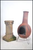 A large 20th century terracotta cylindrical Chiminea - outdoor fire being raised on a cast metal