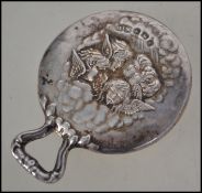 A silver hallmarked pocket mirror - pendant of hammered form having winged cherub -maidens in relief