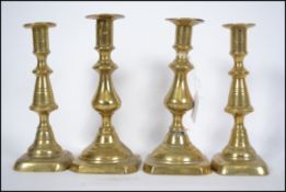 A group of 4 19th century brass candlesticks to include to include 2 pairs, each with single sconces