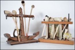 A collection of vintage clay smoking pipes being set within two stands both with HMS Victory