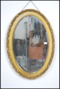 An early 20th century gilt rococo oval wall mirror having inset central bevelled edge glass mirror