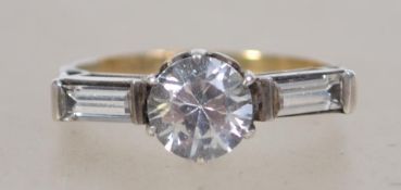 An 18ct gold and diamond ring. Large central round cut diamond approx 50pnts having inset baguette