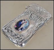 A silver vesta case having an embossed design with inset nude erotic pictorial enamel to centre.