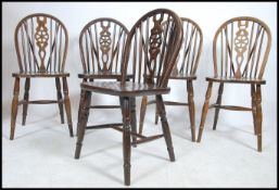 A set of 5 20th century wheelback oak dining chairs raised on turned legs with saddle seats having