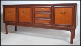 A 1970's retro teak wood sideboard of two tone colour having brass swing handles to the drawers