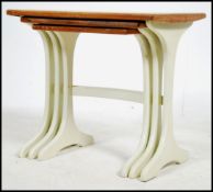 A 1970's G-Plan teak wood nest of tables raised on painted shaped supports with bow stretchers to