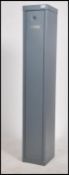 A contemporary metal upright gun cabinet in grey having full length door complete with the keys.