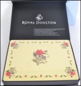 A cased set of  unused table placemats from Royal Doulton depicting floral motifs to the centre.