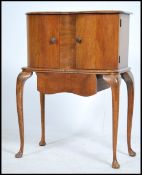 A 1940's walnut Queen Anne revival side cabinet being raised on cabriole legs with pad feet having a