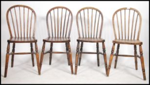 A set of 4 20th century beech and elm wheelback dining chairs being raised on turned legs united