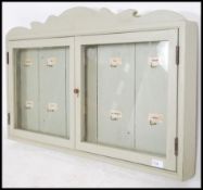 A 20th century shabby chic estate key cupboard being painted grey with twin glazed doors having