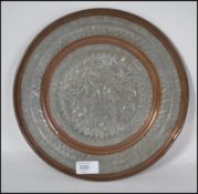 A 20th century brass, copper and silvered circular plate of Kashmir / Indian origin with scenes of