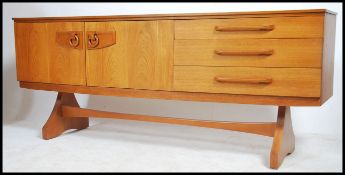 A retro 20th century bow front teak sideboard comprising a series of drawers and cupboards raised on