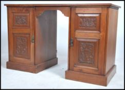 An Edwardian walnut twin pedestal office desk raised on plinth bases with cupboards having carved
