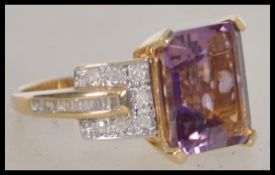 A 14ct yellow gold amethyst and diamond ladies ring. The square cut amethyst flanked by round cut
