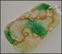 A Chinese jade carved pendant in the form of dragons / dogs of fu having a silver bale clasp atop.