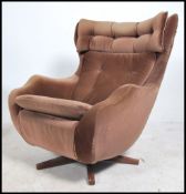 A 1960's Parker Knoll large batwing swivel egg chair - armchair being raised on a teak quadruped