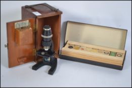 A vintage cased microscope together with a box of scientific glass slides dating from the early 20th