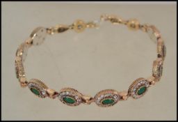 A 20th century gilded silver and cz adorned faux emerald ladies bracelet of roundel form being bar