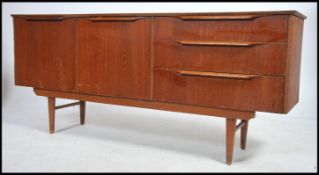 A retro 1970's teak wood sideboard dresser being raised on tapered legs with wide body comprising