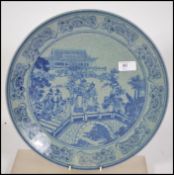 A large Chinese blue and white charger plate with scenes of merchantmen and scholars on bridge in