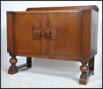 A 1930's Art Deco oak sideboard having shaped supports with a series of drawers and cupboards having