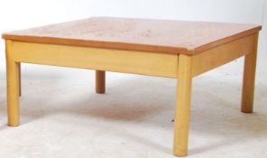 A mid century Ercol blond wood square coffee table raised on turned legs with fitted frieze frame