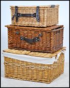 A stack of 3 20th century whicker baskets each with hinged tops and straps
