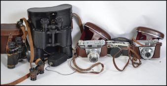 A collection of vintage 35mm cased cameras together with two pairs of vintage binoculars.