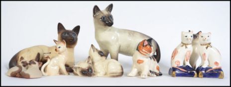 A collection of Beswick and Royal Doulton cat figurines to include Siamese, Beswick No 1559. Also
