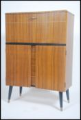 A 1950's walnut cocktail cabinet raised on ebonised tapered supports having articulated top with
