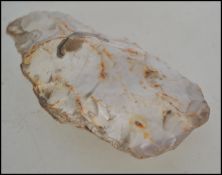 A Neolithic hand carved stone hand axe with remains of Victorian collectors label to one side.