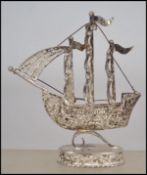 An unusual silver filigree worked figurine of a tall ship - galleon being raised on an oval