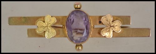 An Edwardian 9ct gold and amethyst set bar brooch, decorated with clover leaves to each side of