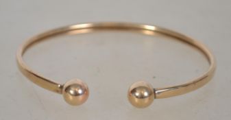 A 9ct gold ladies slave bangle - bracelet with ball finial ends having metal core. Total weight 5.