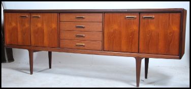 A good 1970's Youngers teak sideboard being raised on tapered supports with a series of drawers
