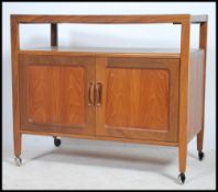 A 1970's retro G-Plan type extending teak wood serving trolley being raised on castors to the base
