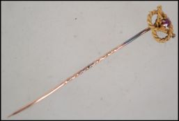 A 15ct god ( stamped 15ct ) having a rope twist knot design with a central mounted red stone.
