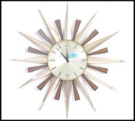 A vintage mid century sunburst retro wall clock with  teak and gilded metal rays with silvered