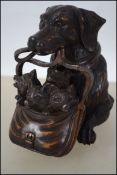 A a carved Black Forest style inkwell in the form of a dog carrying her puppies in a satchel bag