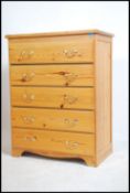 A pine country contemporary chest of drawers having an upright body with brass handles to the