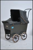 An early 20th century childs pram with deep belly crib with leather hood, green painted body on