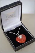 A silver heart shaped apple coral pendant necklace on silver chain cased. Measures 18 inches.