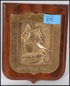 A mid century heavy cast brass wall plaque on a ha