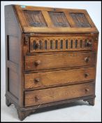 An Ercol Old Colonial / Jacobean revival oak and elm bureau having linen fold fall front writing