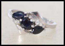 A white metal sapphire ladies ring. The ring with round cut sapphire flanked by 2 marquise cut