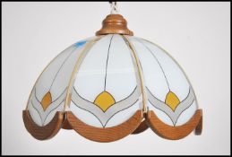 A pair of retro 1970's ceiling lights having frosted and colored glass half moon shades having oak