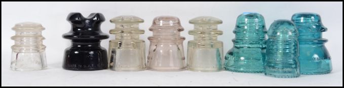 A group of 8 vintage American electricity glass pylon insulators in green, brown, and clear glass.