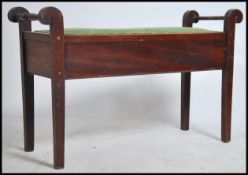 An Edwardian mahogany duet piano stool being raised on squared legs with hinged top and handles to