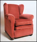 An Edwardian velour upholstered Chesterfield wingback armchair with pad feet upholsted in a pink